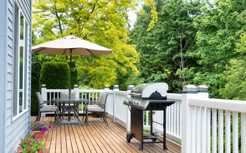 Outdoor furniture, grill, and potted plants on a patio near several trees on a Winston-Salem property.
