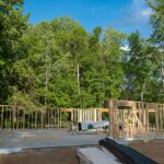 A new house being built in Winston-Salem with tall trees in the background. Proper planning is important to avoid harming these trees during construction.