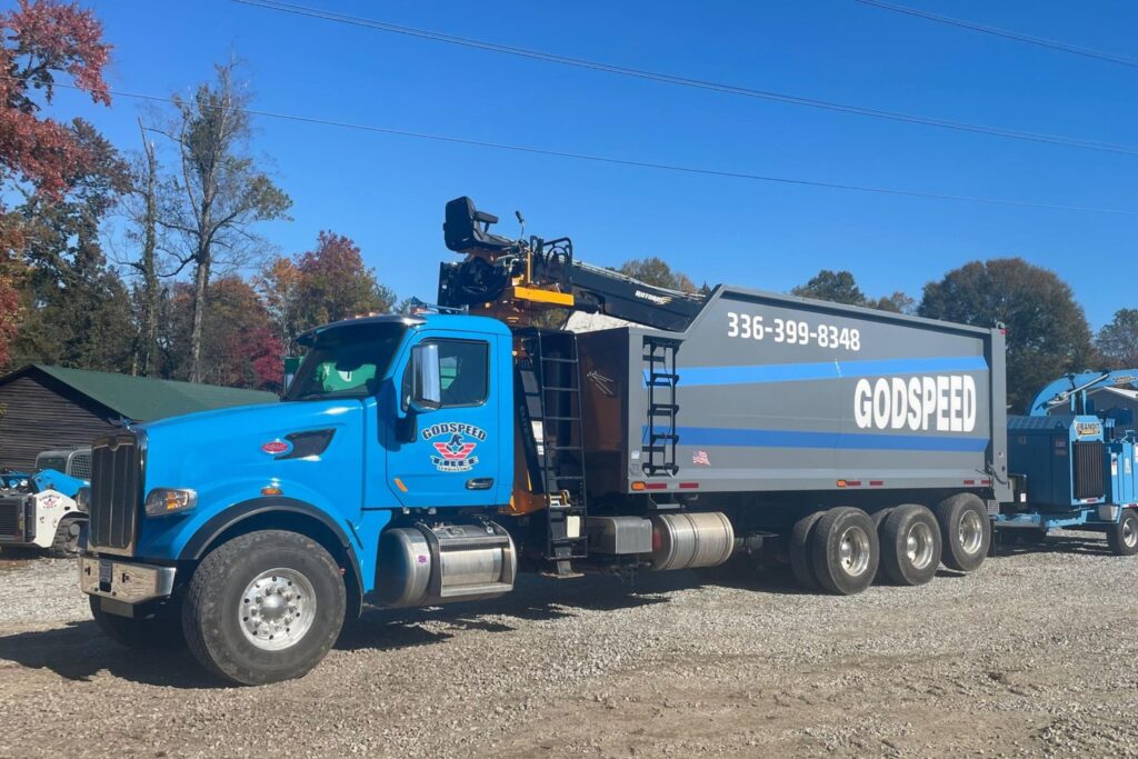 Godspeed Tree Service grapple truck with chipper, ready for storm cleanup and emergency response in Winston-Salem.